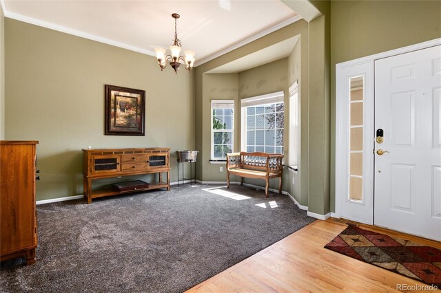 entryway with a chandelier, wood finished floors, baseboards, and ornamental molding