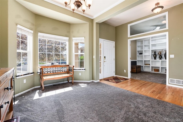 entryway featuring healthy amount of natural light, a chandelier, wood finished floors, and carpet