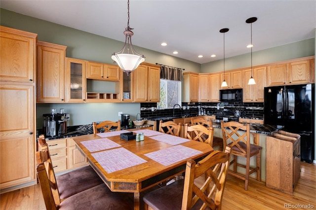 kitchen featuring black appliances, light brown cabinets, light wood-style floors, glass insert cabinets, and decorative backsplash