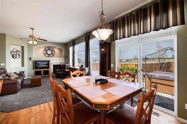 dining space featuring light wood-style flooring, a ceiling fan, and a fireplace