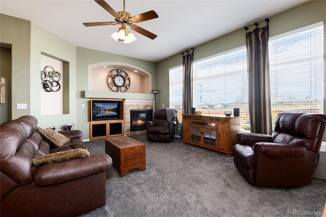 carpeted living room featuring ceiling fan, a tiled fireplace, and vaulted ceiling