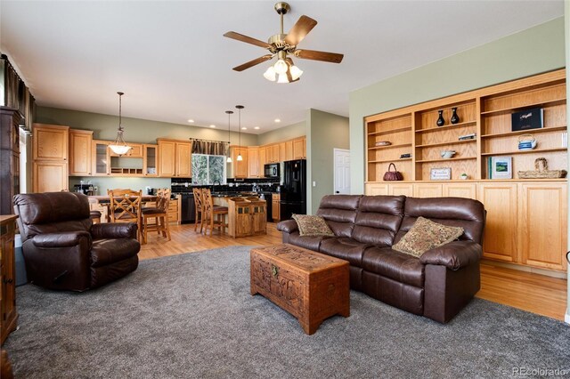 living room with light wood-type flooring and a ceiling fan