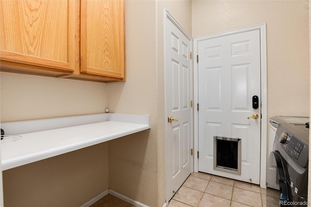 washroom featuring cabinet space, washer and clothes dryer, and light tile patterned flooring