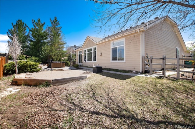 back of house featuring a covered hot tub and fence