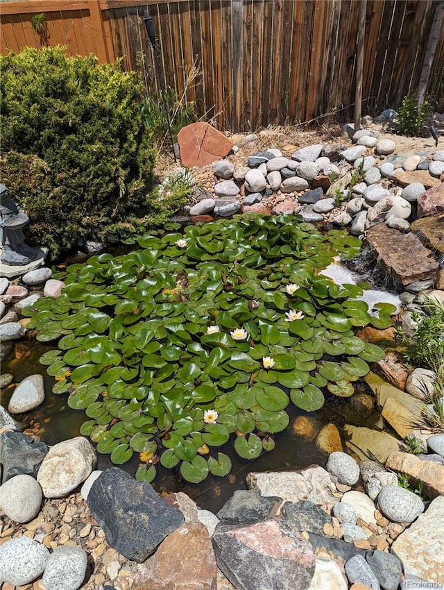 view of yard featuring fence and a garden pond