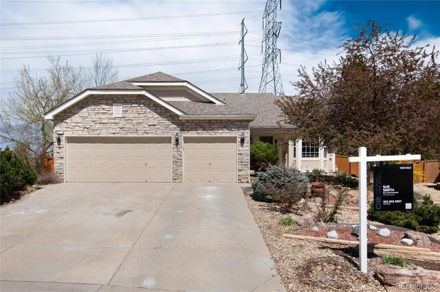 view of front of home with a shingled roof, driveway, stone siding, and an attached garage