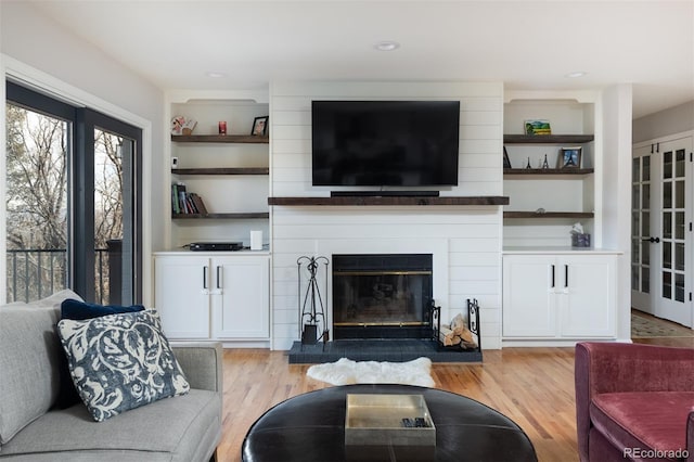 living room with built in features and light wood-type flooring