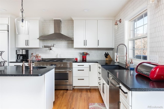 kitchen featuring pendant lighting, wall chimney exhaust hood, stainless steel appliances, and white cabinets