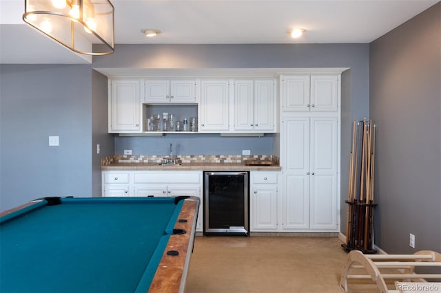 kitchen with tasteful backsplash, sink, beverage cooler, and white cabinets