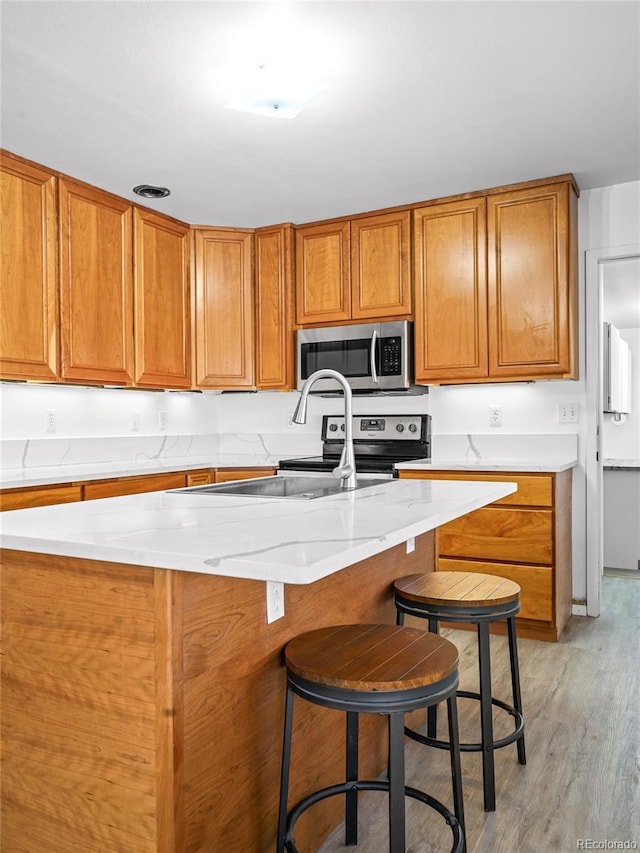 kitchen with a kitchen breakfast bar, stainless steel appliances, and light hardwood / wood-style flooring