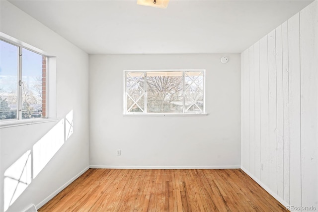 unfurnished room with wood walls and light wood-type flooring