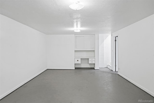 unfurnished room with concrete flooring and built in desk