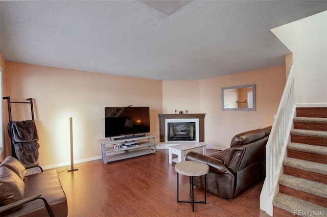 living area with stairway, baseboards, a textured ceiling, and wood finished floors