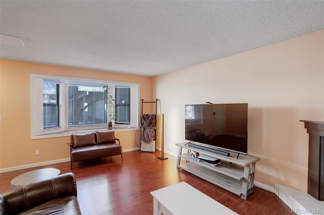 living room featuring wood finished floors, baseboards, and a textured ceiling