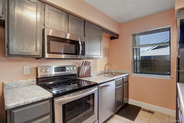 kitchen with visible vents, light countertops, light tile patterned floors, stainless steel appliances, and a sink