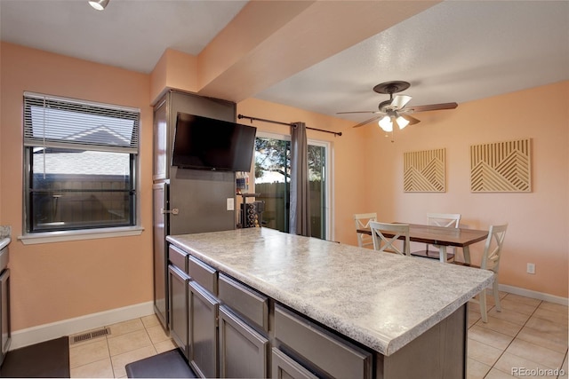 kitchen featuring a peninsula, light tile patterned floors, light countertops, and baseboards