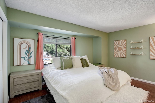 bedroom with baseboards, a textured ceiling, and dark wood-style floors