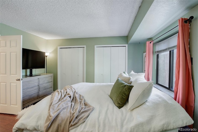 bedroom featuring wood finished floors, two closets, and a textured ceiling