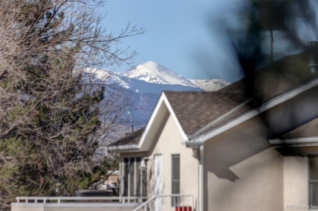 view of side of home featuring a mountain view, roof with shingles, and stucco siding