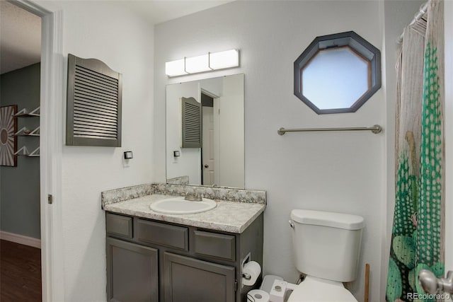 full bath with vanity, a shower with curtain, wood finished floors, baseboards, and toilet