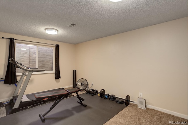 exercise area with baseboards, carpet, visible vents, and a textured ceiling