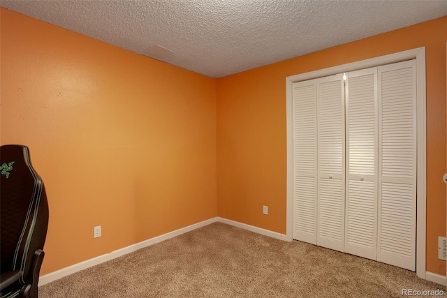 unfurnished bedroom featuring a closet, a textured ceiling, baseboards, and carpet floors