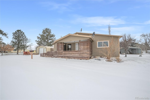 view of front facade featuring a garage, a carport, and a storage unit