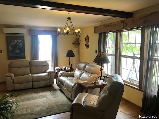 living room featuring plenty of natural light, an inviting chandelier, a wall mounted air conditioner, and light wood-type flooring