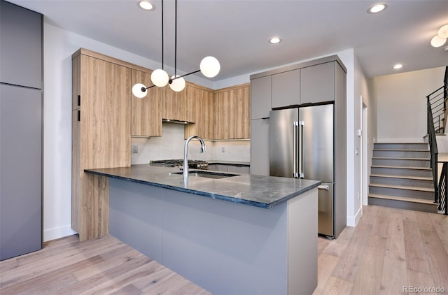 kitchen featuring dark stone countertops, kitchen peninsula, pendant lighting, high end refrigerator, and sink