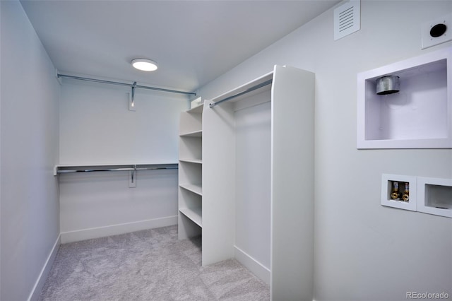 spacious closet featuring light colored carpet