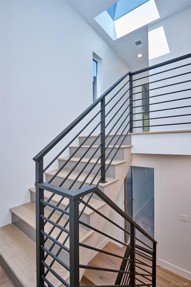 stairway featuring a skylight and hardwood / wood-style floors