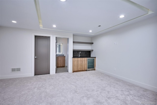 unfurnished living room with beverage cooler, light carpet, and indoor wet bar