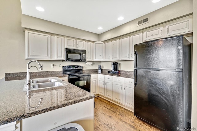 1099 S Walden Way Unit 205, Aurora, CO 80017 - kitchen with black appliances, light wood-style flooring, recessed lighting, and white cabinetry