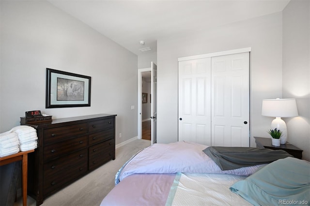 bedroom with baseboards, a closet, and light colored carpet