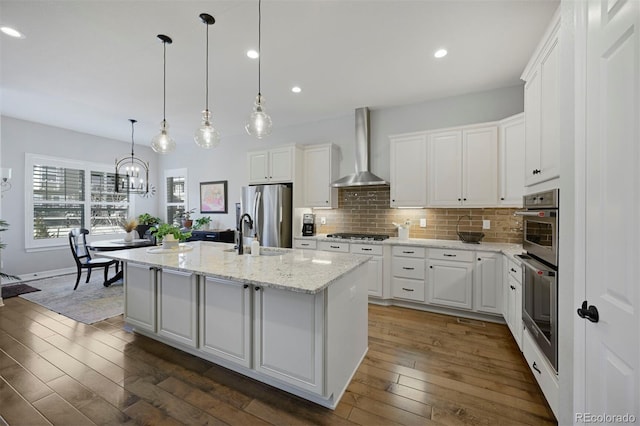 kitchen with wall chimney range hood, dark wood finished floors, stainless steel appliances, and decorative backsplash