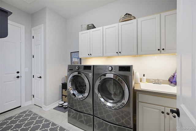 laundry area featuring washing machine and clothes dryer, light tile patterned floors, cabinet space, a sink, and baseboards