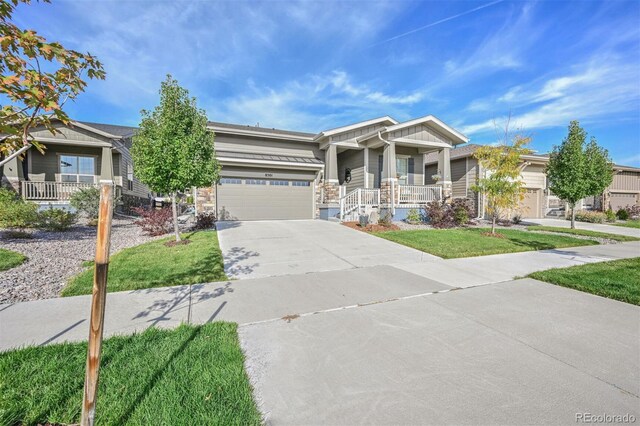 view of front of home featuring driveway, covered porch, a garage, and a front yard