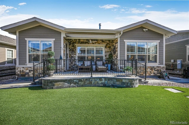 rear view of property with stone siding, a yard, and ceiling fan