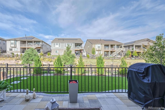 view of patio featuring area for grilling, fence, and a residential view