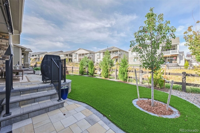 view of yard featuring a patio area, fence, and a residential view