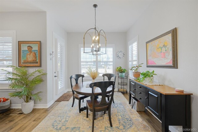 dining space featuring light wood-style flooring, a chandelier, and baseboards