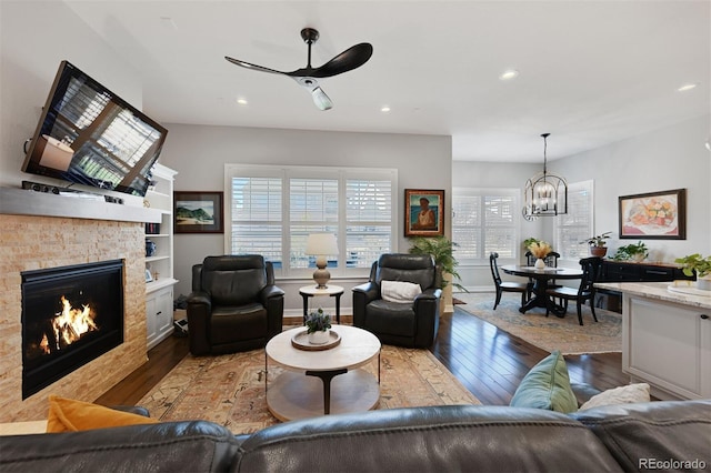 living area featuring ceiling fan with notable chandelier, a lit fireplace, hardwood / wood-style floors, and recessed lighting