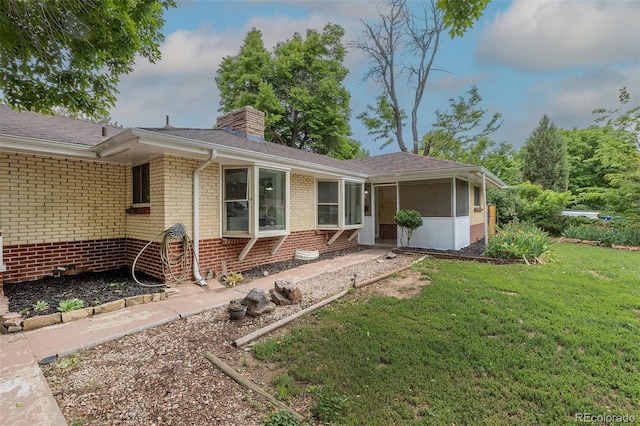 5810 S Greenwood St, Littleton, CO 80120 - view of front of home with brick siding, a chimney, a front lawn, and a sunroom