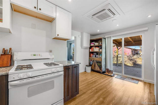 kitchen featuring white range with gas cooktop, light stone counters, white cabinets, and light wood-type flooring