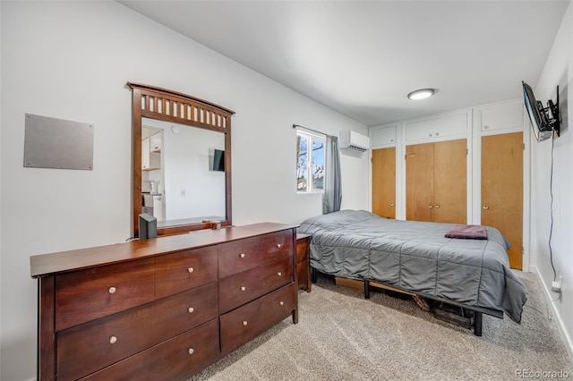 carpeted bedroom with a wall unit AC and multiple closets