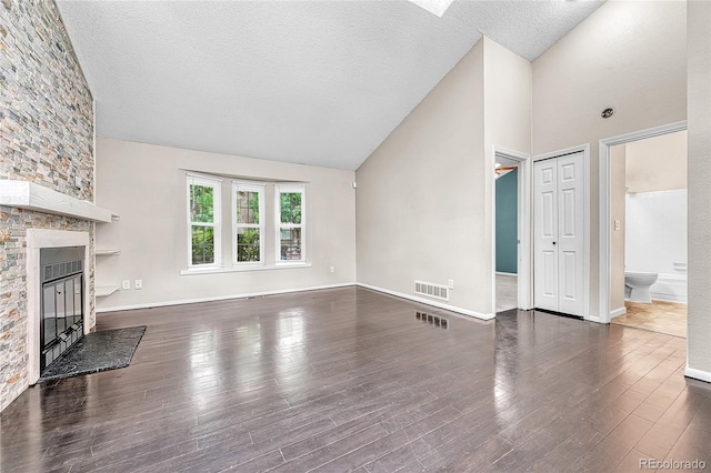 1148 S Ventura Cir Unit H, Aurora, CO 80017 - unfurnished living room with a stone fireplace, a textured ceiling, high vaulted ceiling, wood finished floors, and baseboards