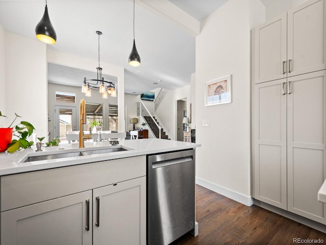 kitchen featuring pendant lighting, dishwasher, sink, dark wood-type flooring, and a notable chandelier