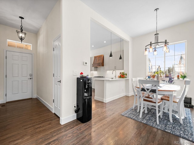 dining area featuring sink, dark wood-type flooring, and a notable chandelier