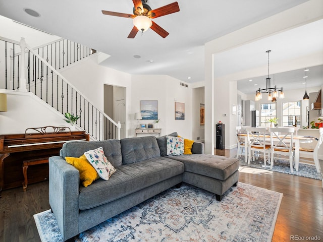 living room with ceiling fan with notable chandelier and dark hardwood / wood-style floors