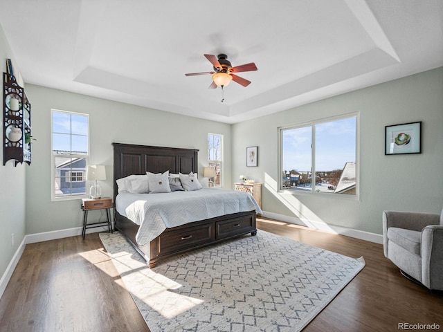 bedroom featuring ceiling fan, hardwood / wood-style floors, and a tray ceiling